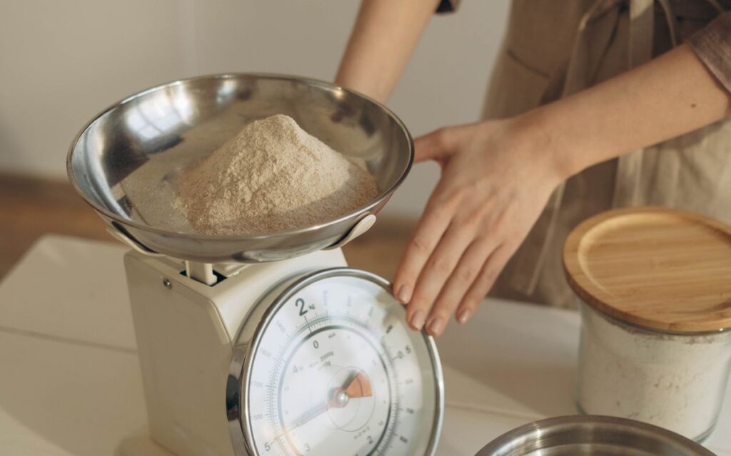 Mulher pesando ingrediente em balanca de cozinha