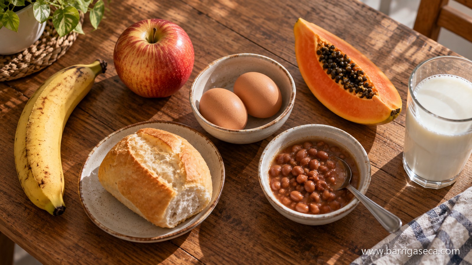 Banana, maca, dois ovos numa tigela, mamao, pao frances, uma tigela de feijao e um copo de leite dispostos numa mesa de madeira