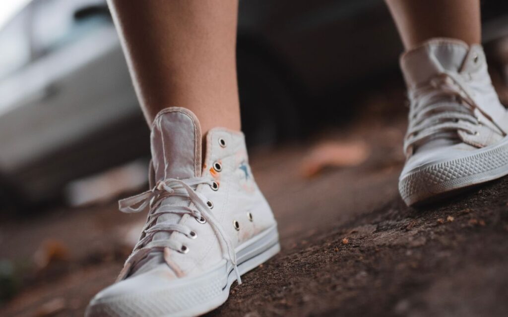Tenis brancos em uma calcada, representando a caminhada diaria