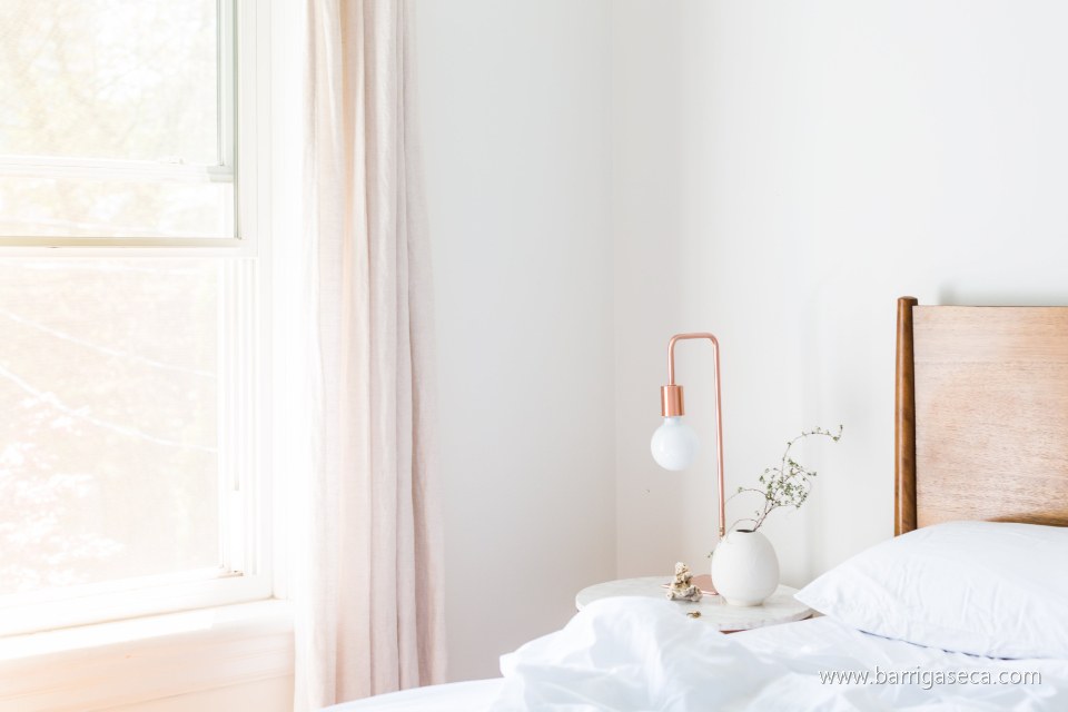 Quarto claro com cama arrumada e luz da manhã
