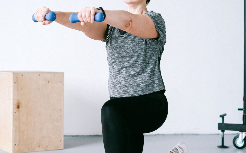 Mulher adulta treinando com halteres em casa, estrategia recomendada na menopausa